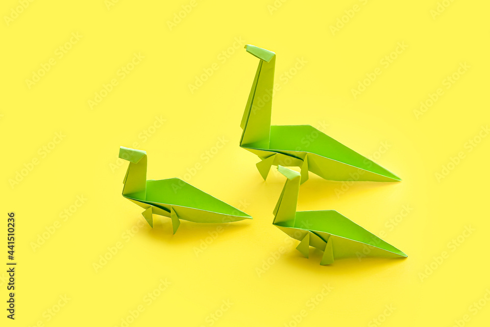 Origami dinosaurs on color background. Concept of uniqueness