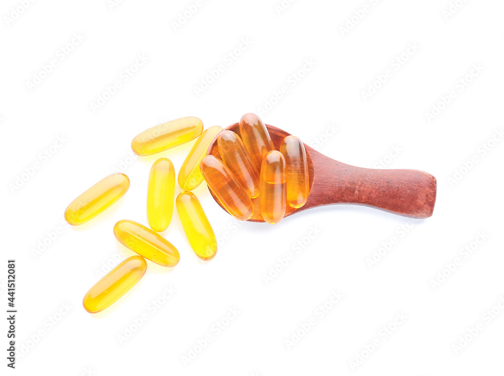 Spoon with fish oil capsules on white background