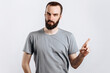 © Daria Lukoiko - Portrait of cheerful young handsome man smiling looking at camera pointing finger upwards on white background with space for advertising mock up