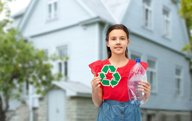 Wall Mural - waste sorting and sustainability concept - smiling girl holding green recycling sign and plastic bottle over house background