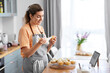 © Syda Productions - culinary, bake and cooking food concept - happy smiling young woman with baking bag making cupcake topping on kitchen at home