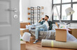 © Syda Productions - moving, people and real estate concept - happy smiling man with boxes calling on smartphone at new home
