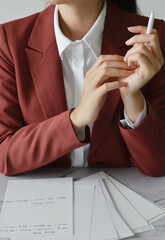 Businesswoman in burgundy suit attending and taking notes during meeting 