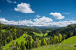 classical Emmental landscape with farm houses in the hills on a spring day in front of the Bernese Alps