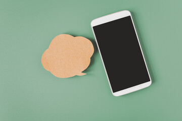 white smart phone with clipping path on touchscreen , blank grunge brown speech bubble  paper on dark green background , communication , network, social distancing concept