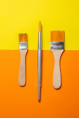 brushes and roller to paint on smooth orange and yellow background