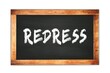 REDRESS text written on wooden frame school blackboard.