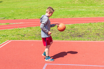 Boy preparing ball shooting at playground.Boy performs shot at basketball game on the playground during sunny summer day