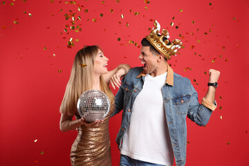 Wall Mural - Happy couple with disco ball and confetti on red background