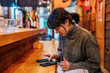 © ADDICTIVE STOCK - Young woman browsing smartphone in cafe