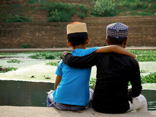 Two muslim kids friend sitting at river bank, lovely friendship concept.