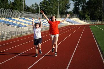 Wall Mural - Little girl running on the stadium with a coach