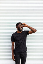 Cheerful Black Male Standing Near Striped Wall