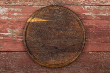 Wall Mural - Circle cutting board on a red wooden table. Food preparation tool and kitchen utensils.