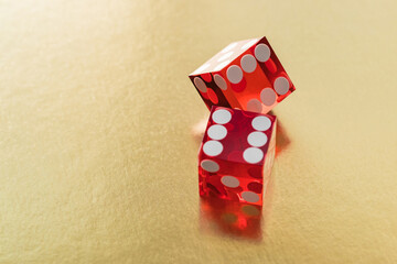 Two red glass dice on a gold background with space to copy. A dice on the edge and a six.