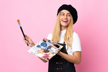 Wall Mural - Young artist woman holding a palette over isolated pink background