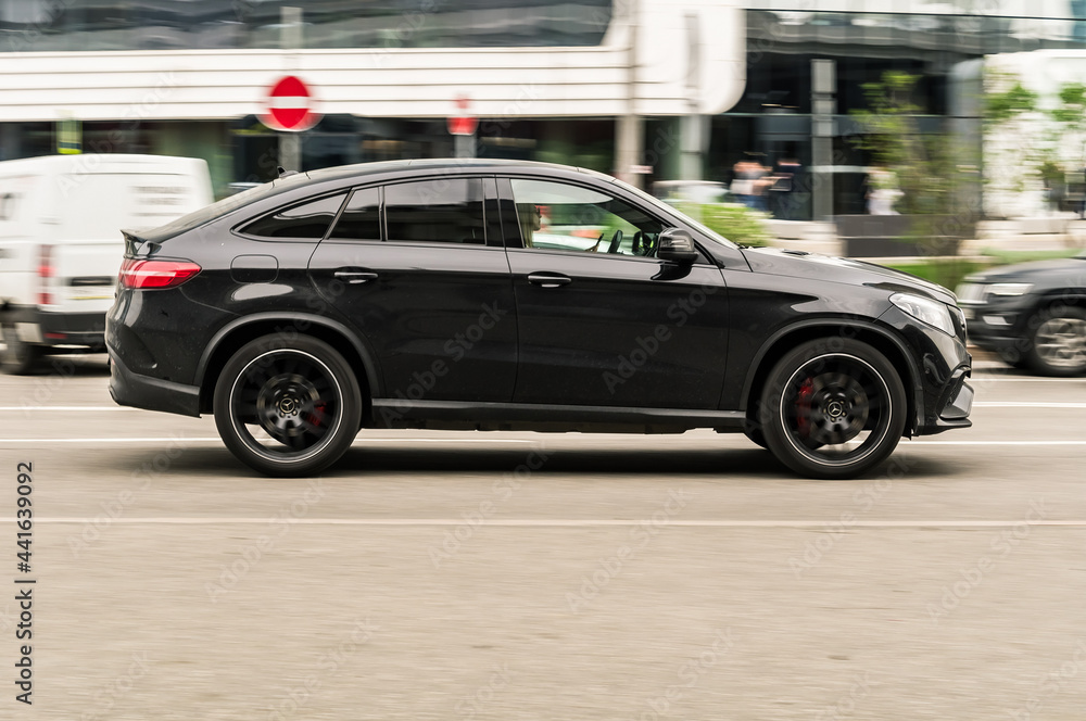 Gle Fast One fast moving black Mercedes GLE coupe SUV is driving on a city road. A ...
