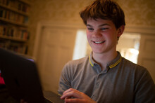 Happy Teenage Boy Using Laptop At Home