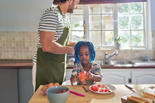 Father And Daughter Eating Fruit In Kitchen