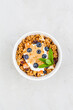 Bowl of granola with blueberries, peanut paste and yogurt on grey top view.