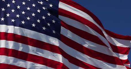 Wall Mural - 4k Slow Motion Real American Flag Waving In Wind Against a Deep Blue Sky