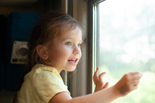 A Little Girl Looks Out The Train Window With Interest. Travelling With A Child. Vacation. Curiosity. Summer.