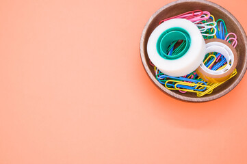 Sticker - Top view of colorful paper clips and adhesive tapes in a wooden bowl