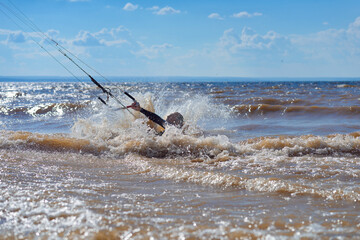 Kiteboarder surfing waves with kiteboard on a sunny summer day.