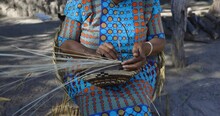 Close-up Cropped View Of A Woman Weaving A Traditional Basket Made From The Fan Palm Leaf Fibre