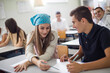 © liderina - Helping a friend. Teenagers students sitting in the classroom working exam.
