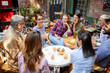 © luckybusiness - group of caucasian young and senior people, male and female, sitting together in outdoor cafe talking, laughing, smiling.
