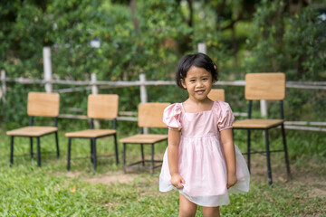 Wall Mural - Smiling little Asian girl standing outdoor.