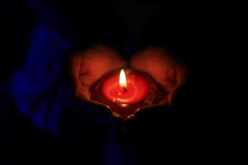 Burning candle in the hands of a girl. Christmas candles. Candle light glowing in woman's hands. Praying, faith, religion concept.