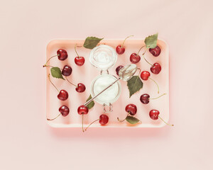 Wall Mural - Summer food composition with plastic tray with season, farm cherries and natural yogurt on a pink background. Healthy kid or school food and benefits of seasonal fruits concept. Flat lay