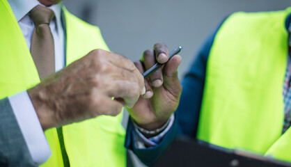 Wall Mural - Engineer discussing the structure of the building with architects colleague at construction site. Signing document. Focus is on hands.