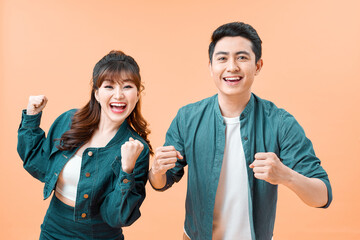 Wall Mural - Portrait of an attractive cheerful young couple wearing casual clothing standing isolated over color background, celebrating success