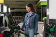 © LIGHTFIELD STUDIOS - smiling woman in denim clothes fueling car on gas station