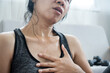 tired Asian woman having heart attack after doing sport hand holding her chest pain that sweat from overtraining