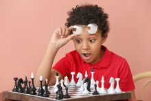 Cute African-American Boy Playing Chess On Color Background