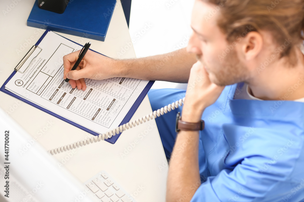Male receptionist talking by telephone in clinic