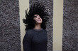 © ADDICTIVE STOCK - Carefree woman with flying curly hair in street
