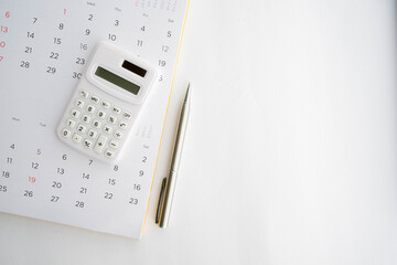 close up top view on calculator with calendar and pen on white background with copy space for business and financial activity monthly concept