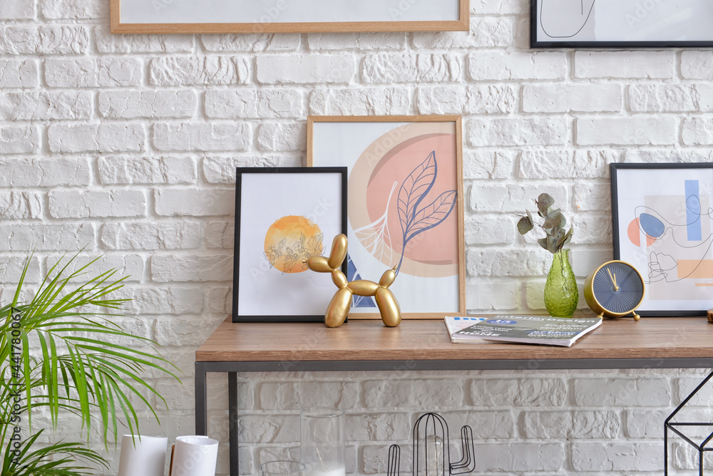 Table with pictures and decor near brick wall