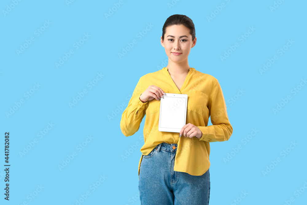 Beautiful young woman with tablet computer on color background