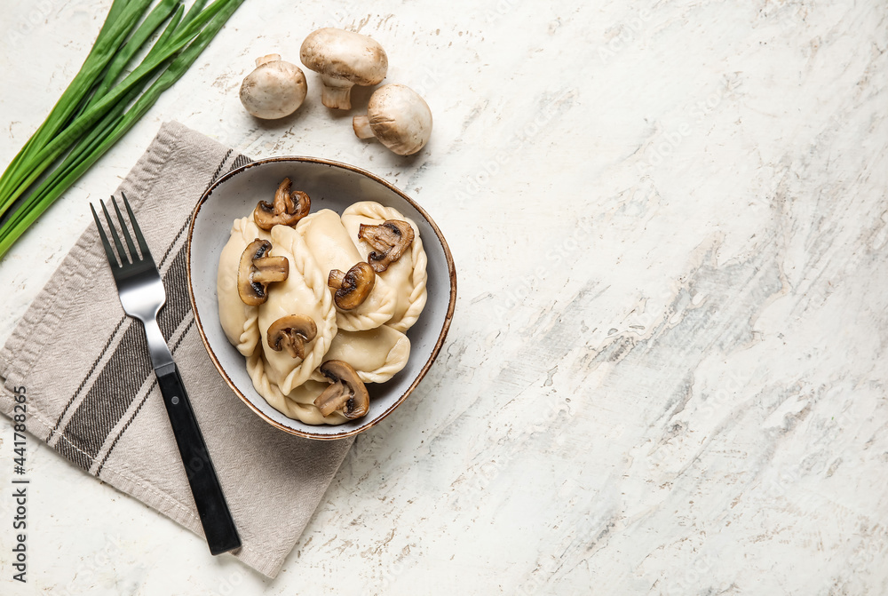 Bowl with tasty dumplings and fresh ingredients on light background