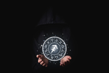Wall Mural - women's hand in the dark holding glowing astrological signs of the zodiac in a circle