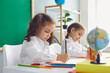 © Studio Romantic - Back to school. Children schoolchildren write while sitting at the table in the classroom.