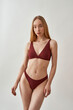 © Svitlana - Attractive young slim caucasian woman with beautiful perfect body wearing burgundy underwear posing isolated over light gray background