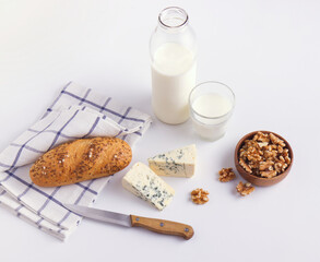 Two portions of blue cheese, white table background, bread and milk.