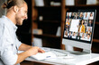 © Kateryna - Online education. Smart caucasian guy gains knowledge watching lesson online. Young man takes notes during webinar, listening lecture on video call. Female teacher and students on a screen